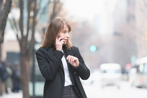 Caucasian young woman talking with someone with smartphone on ear