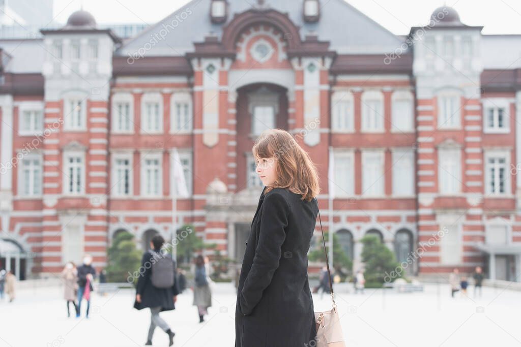 A young woman sightseeing a brick Tokyo Station (Tokyo, Japan)