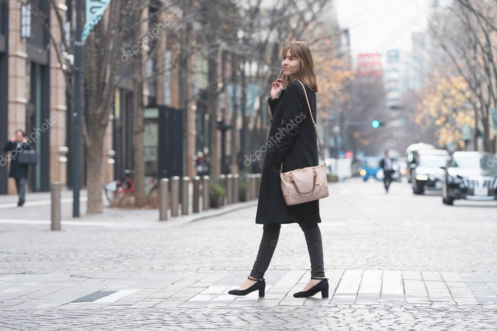 Caucasian young woman walking in the business district of Tokyo, Japan