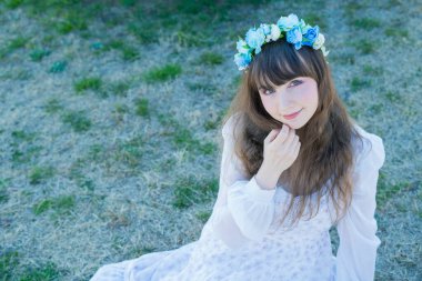 Yeşil topraklarda mavi Corolla giyen beyaz bir kadının portresi.