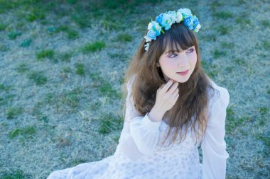 Yeşil topraklarda mavi Corolla giyen beyaz bir kadının portresi.