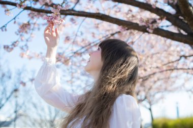 Genç beyaz kadın portresi, kiraz çiçekleri açmış.