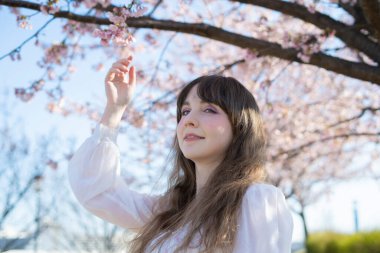 Genç beyaz kadın portresi, kiraz çiçekleri açmış.