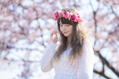 Genç beyaz kadın portresi, kiraz çiçekleri açmış.