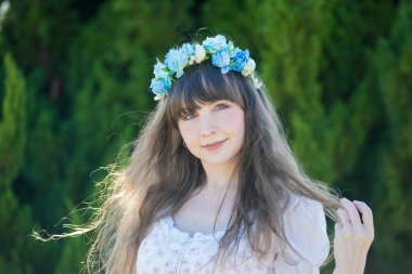 Yeşil topraklarda mavi Corolla giyen beyaz bir kadının portresi.