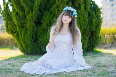 Yeşil topraklarda mavi Corolla giyen beyaz bir kadının portresi.