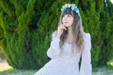 Yeşil topraklarda mavi Corolla giyen beyaz bir kadının portresi.