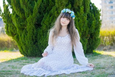 Yeşil topraklarda mavi Corolla giyen beyaz bir kadının portresi.