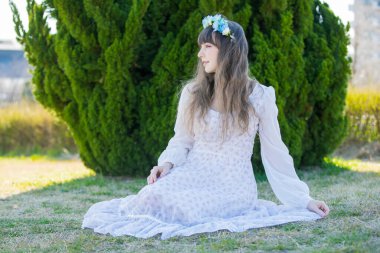 Yeşil topraklarda mavi Corolla giyen beyaz bir kadının portresi.