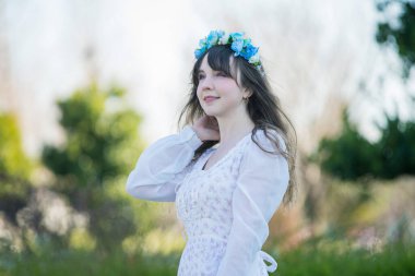 Yeşil topraklarda mavi Corolla giyen beyaz bir kadının portresi.