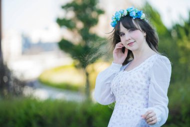 Yeşil topraklarda mavi Corolla giyen beyaz bir kadının portresi.