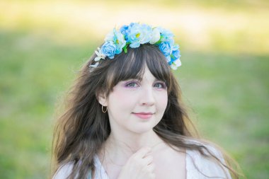 Yeşil topraklarda mavi Corolla giyen beyaz bir kadının portresi.