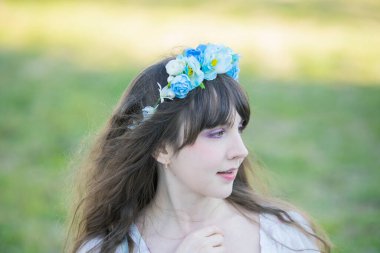 Yeşil topraklarda mavi Corolla giyen beyaz bir kadının portresi.