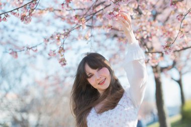 Genç beyaz kadın portresi, kiraz çiçekleri açmış.