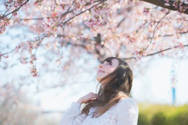 Genç beyaz kadın portresi, kiraz çiçekleri açmış.