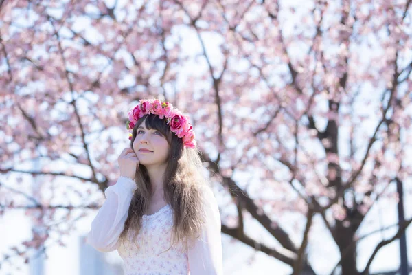 Genç beyaz kadın portresi, kiraz çiçekleri açmış.