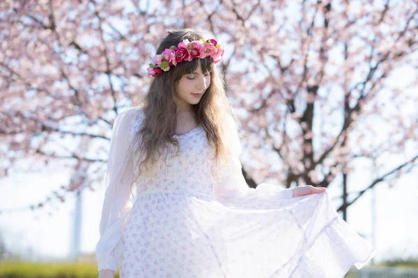 Portrait of young caucasian woman with cherry blossoms in full bloom