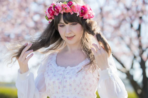 Portrait of young caucasian woman with cherry blossoms in full bloom