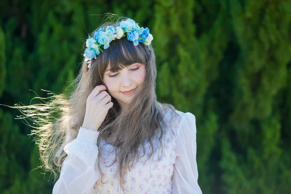 Yeşil topraklarda mavi Corolla giyen beyaz bir kadının portresi.