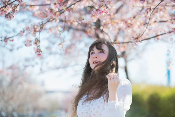 Portrait of young caucasian woman with cherry blossoms in full bloom