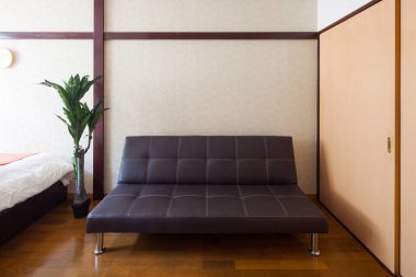 Temiz ve rahatlatıcı bir oturma odasına yerleştirilmiş basit bir kanepe.