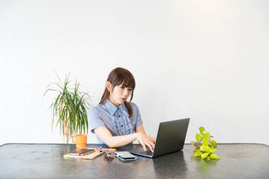 Asyalı kadın evdeki oturma odasında masa başı işi yapıyor.