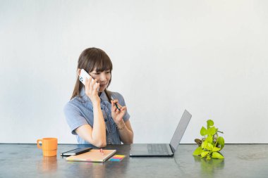 Asyalı kadın evdeki oturma odasında masa başı işi yapıyor.