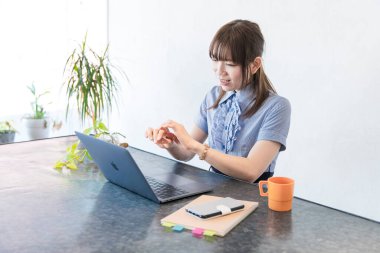 Asyalı kadın evdeki oturma odasında masa başı işi yapıyor.