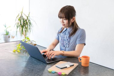 Asyalı kadın evdeki oturma odasında masa başı işi yapıyor.