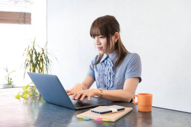 Asyalı kadın evdeki oturma odasında masa başı işi yapıyor.