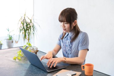 Asyalı kadın evdeki oturma odasında masa başı işi yapıyor.