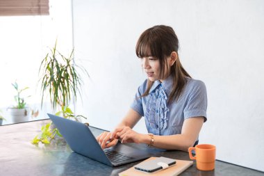 Asyalı kadın evdeki oturma odasında masa başı işi yapıyor.