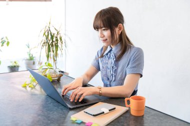 Asyalı kadın evdeki oturma odasında masa başı işi yapıyor.