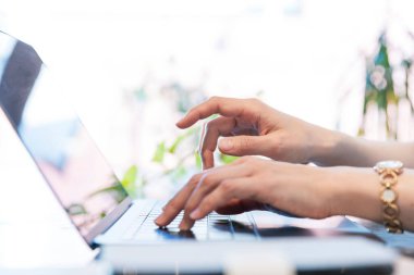 Kapalı işyerindeki klavyeye yazı yazan kadınların yakın plan fotoğrafı.