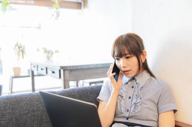 Asyalı kadın evdeki oturma odasında masa başı işi yapıyor.