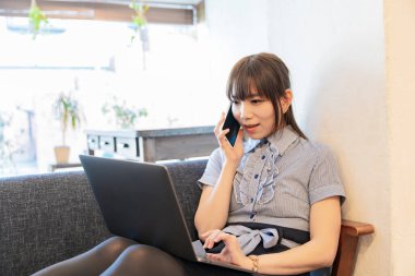 Asyalı kadın evdeki oturma odasında masa başı işi yapıyor.