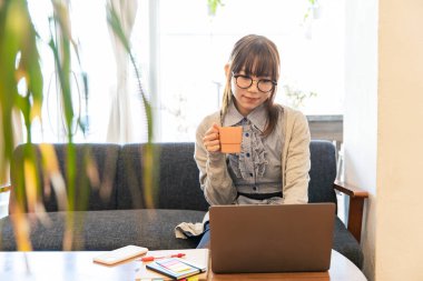 Asyalı kadın evdeki oturma odasında masa başı işi yapıyor.