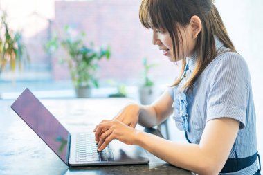 Asyalı kadın evdeki oturma odasında masa başı işi yapıyor.