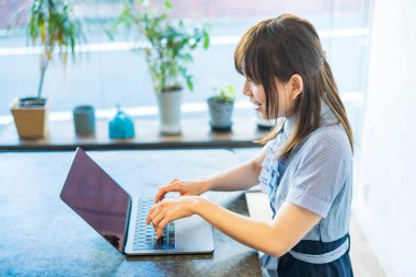 Asyalı kadın evdeki oturma odasında masa başı işi yapıyor.