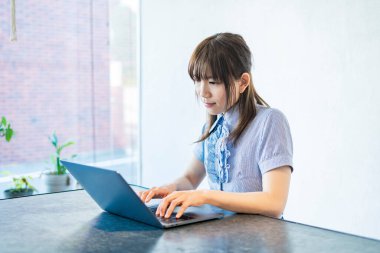 Asyalı kadın evdeki oturma odasında masa başı işi yapıyor.