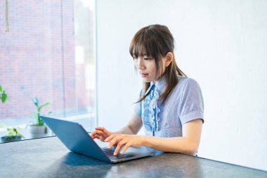 Asyalı kadın evdeki oturma odasında masa başı işi yapıyor.