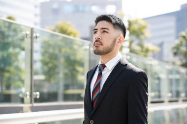 Açık havada duran, sakallı, melez, genç bir iş adamı.