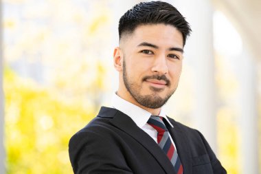 Açık havada duran, sakallı, melez, genç bir iş adamı.