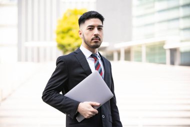 Karışık ırk genç işadamı, takım elbiseli, dizüstü bilgisayar kullanıyor.