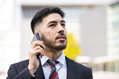 Akıllı telefon kullanan, takım elbiseli, melez, genç bir işadamı.