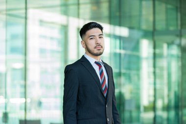 Açık havada duran, sakallı, melez, genç bir iş adamı.