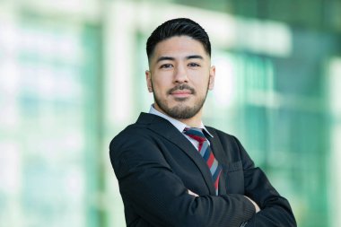 Açık havada duran, sakallı, melez, genç bir iş adamı.