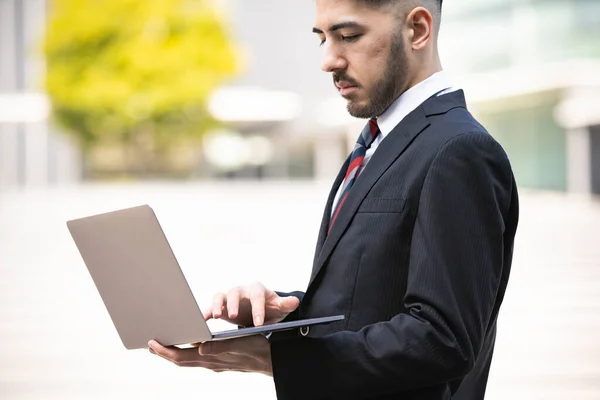 Mixed race young businessman with beard in suit using a laptop