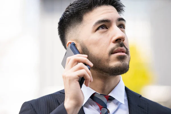 Mixed race young businessman with beard in suit using smartphone