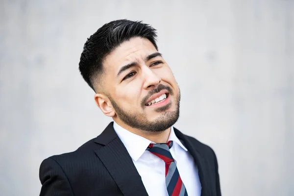 Mixed race young businessman with beard in suit making a creepy smile